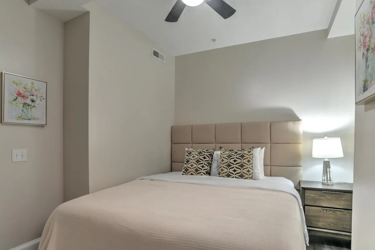 A serene bedroom featuring a neatly made bed adorned with decorative pillows, a bedside lamp casting soft light, and thoughtfully chosen wall art. The atmosphere is calm and welcoming, ideal for unwinding after a day of exploration. Gentle natural light suggests a restful night and easy mornings.
