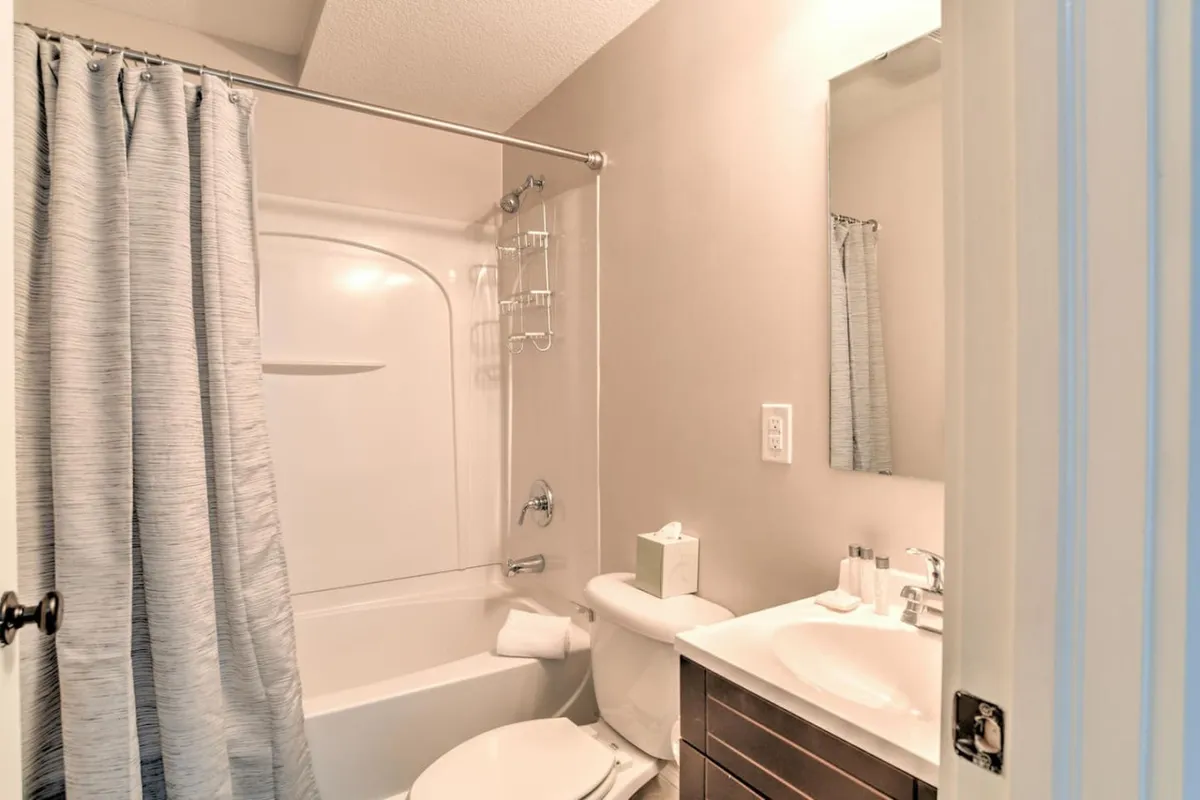 A refreshing bathroom with a bathtub, vanity, mirror, toilet, and shower curtain. The space is clean, calming, and perfectly suited for soothing baths after a long day or a revitalizing morning routine.