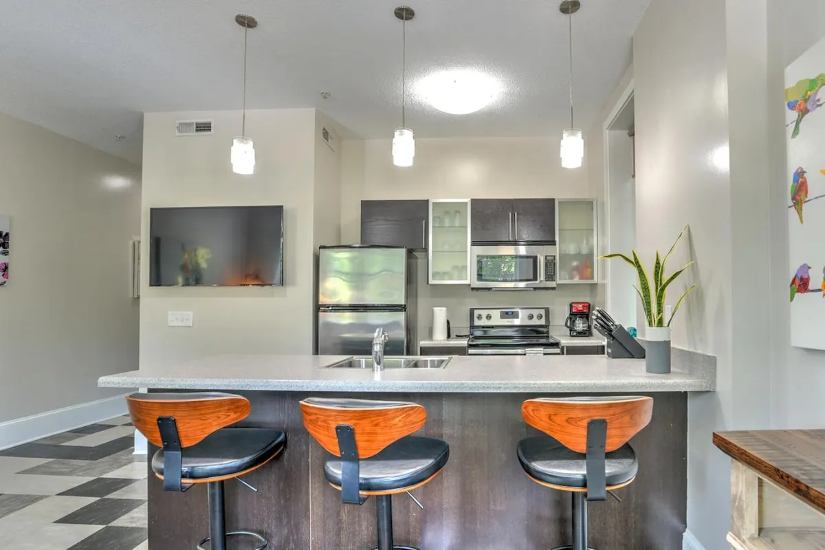 A stylish kitchen area with a center island, bar stools, modern appliances, and contemporary wall art. The space transitions seamlessly from the living area, encouraging entertaining and casual dining in a bright, modern setting.